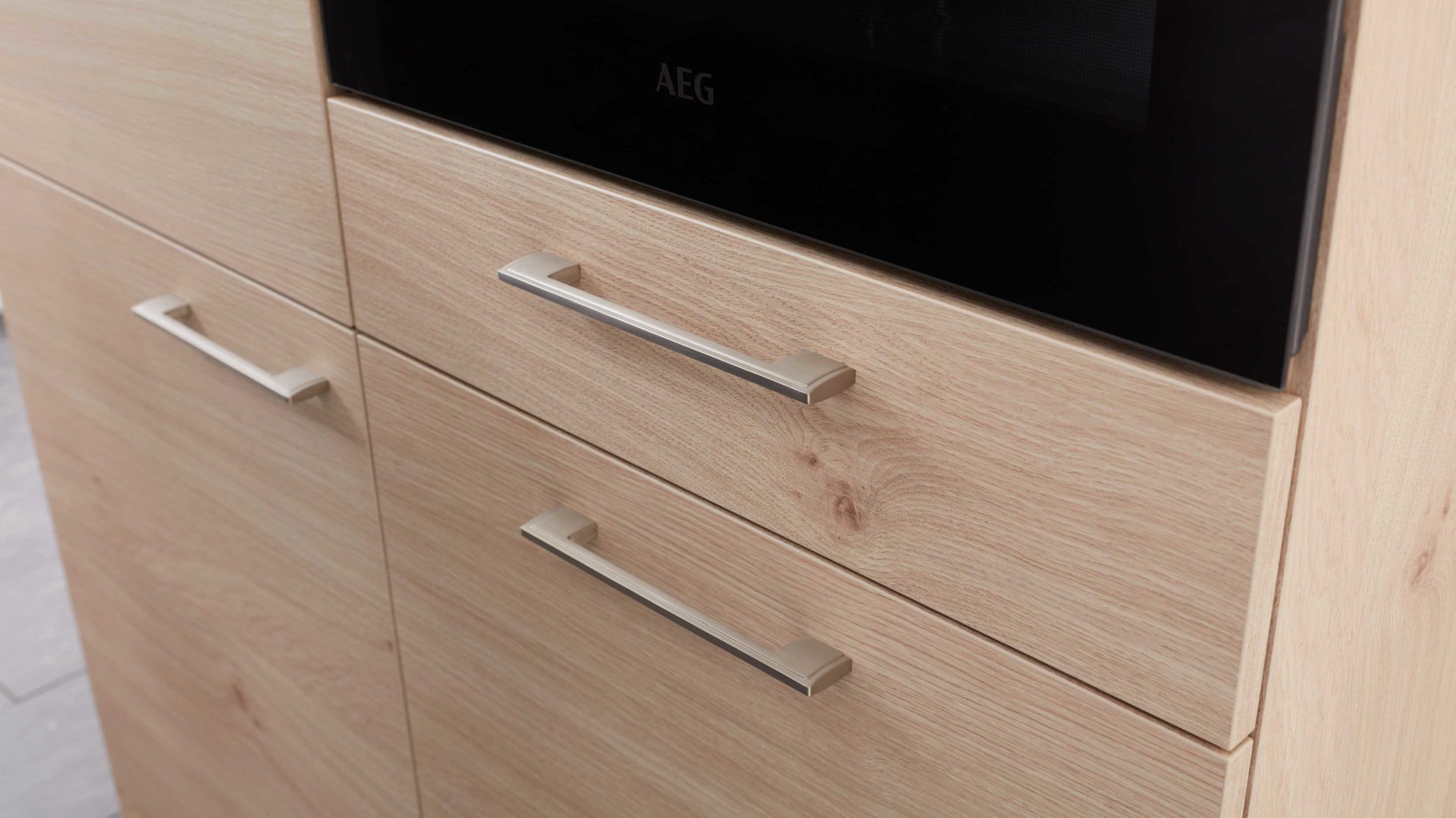 Einbauküche Interliving aus Holz in Holzfarben Interliving Küche Serie 3008 mit AEG Einbaugeräten Stahlgrau & Asteiche – zweizeilig